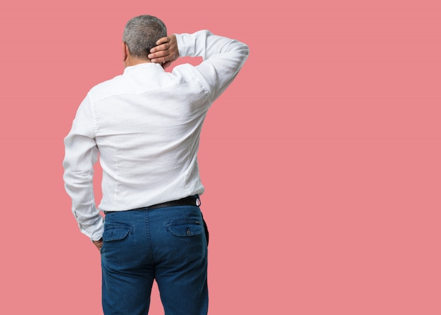 Homme d&#39;âge moyen montrant en arrière, posant et attendant, regardant en arrière