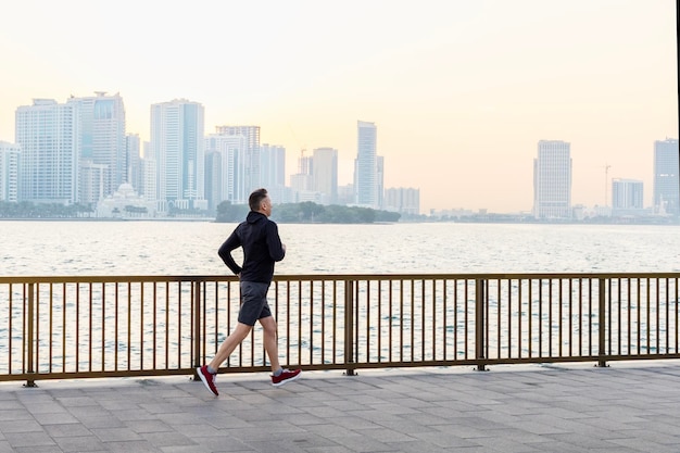 Homme d'âge moyen portant des vêtements de sport courant au bord de la mer Mode de vie sain concept de vie urbaine active