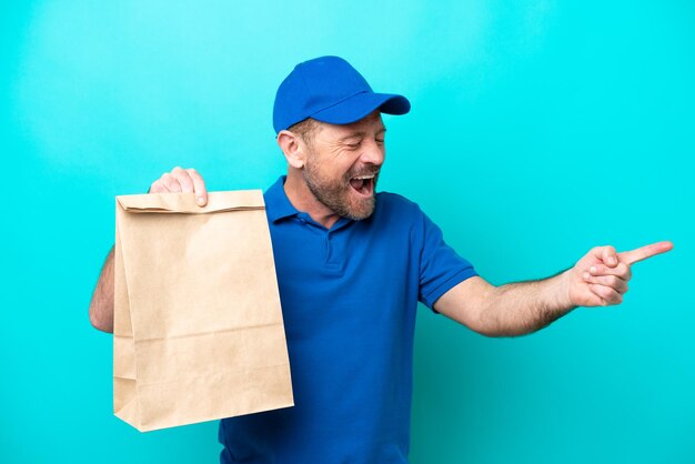 Homme d'âge moyen prenant un sac de plats à emporter isolé sur fond bleu