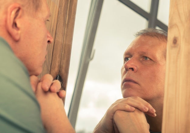 Homme d'âge moyen regardant sérieusement le reflet du miroir, pensant à son âge et à sa vie.