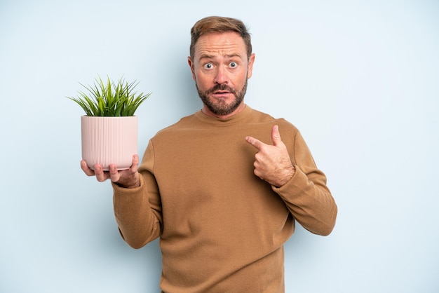 Homme d'âge moyen se sentant heureux et se montrant avec un excité. concept de pot de plante