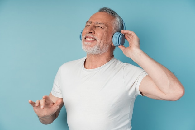 Homme d'âge mûr attrayant dans les écouteurs aime la musique. Homme dansant isolé.