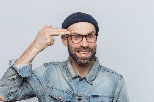 Homme d'âge mûr barbu aux yeux bleus s'amuse, trompe et fait un geste de suicide