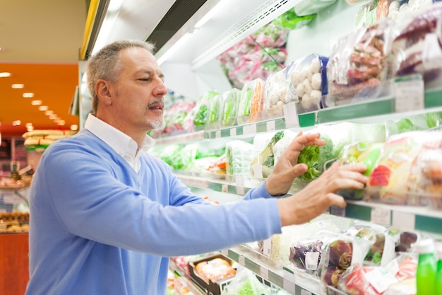 Homme d&#39;âge mûr en choisissant des légumes dans un supermarché