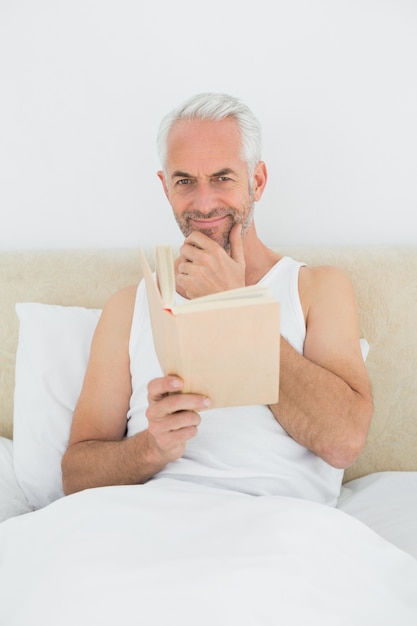 Homme d&#39;âge mûr détendue livre de lecture dans son lit