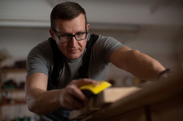 Un homme d'âge mûr portant des lunettes brunes se concentre sur le nettoyage de la surface du comptoir.