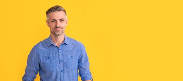 Homme d'âge mûr souriant avec des cheveux grisonnants sur fond jaune