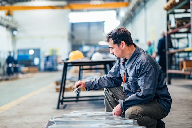 Homme d&#39;âge mûr travaillant avec un instrument de mesure en usine.