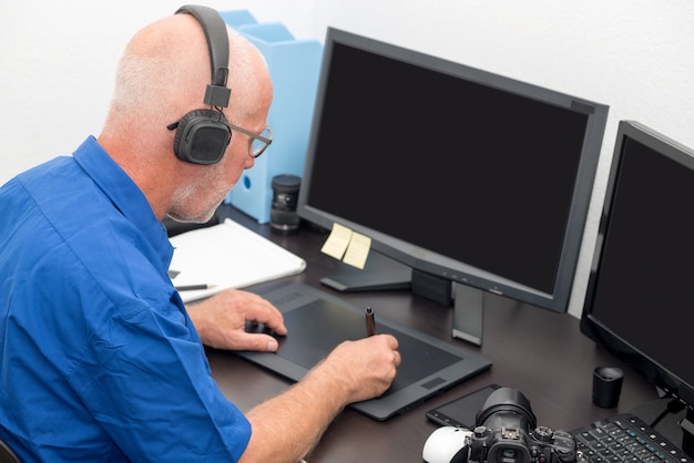 Homme d'âge mûr travaillant avec une tablette graphique dans son bureau