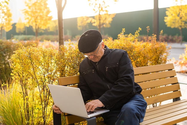 Homme âgé avec ordinateur portable dans le parc d'automne.