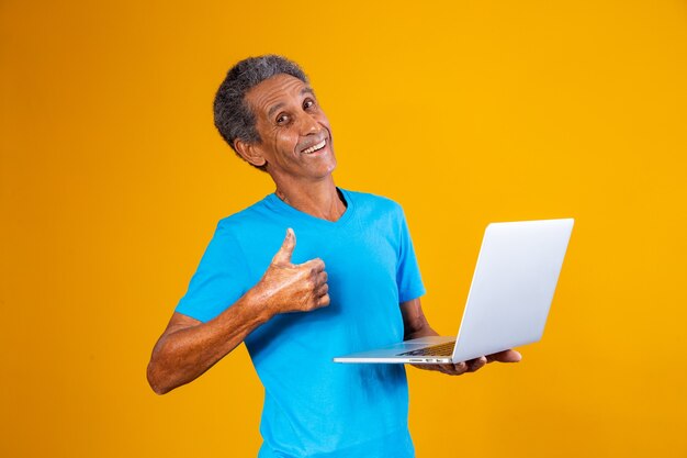 Homme âgé avec un ordinateur portable faisant ses courses ou travaillant en ligne. Homme plus âgé avec son pouce en l'air tenant un ordinateur portable.