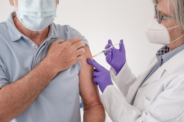 Homme âgé portant un masque chirurgical se faisant vacciner contre le coronavirus covid-19. Concept de vaccination du laissez-passer vert