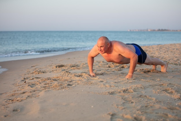 Un homme âgé pousse sur la côte de la mer Sports en mer hommes d'âge moyen