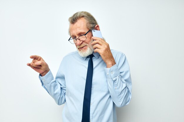 Photo un homme âgé qui parle sur un téléphone intelligent sur un fond blanc