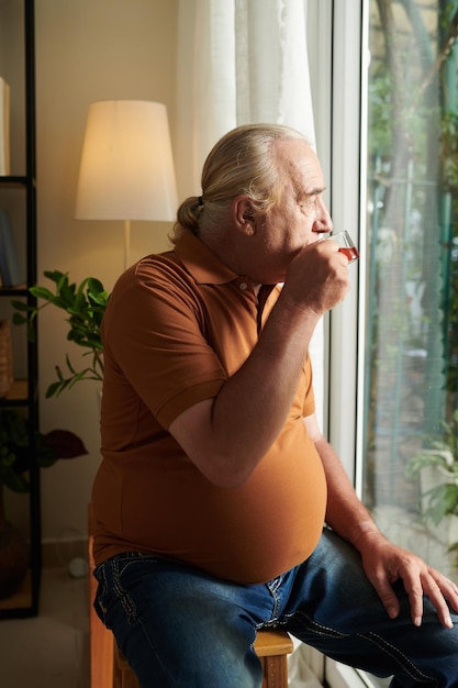 Homme âgé regardant dehors par les portes