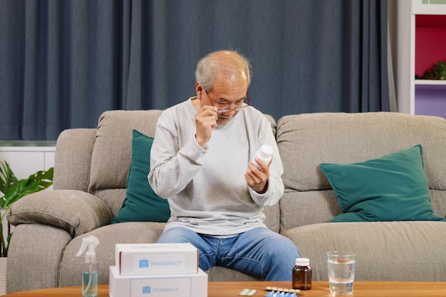 Homme âgé regardant et lisant l'étiquette du médicament à la maison