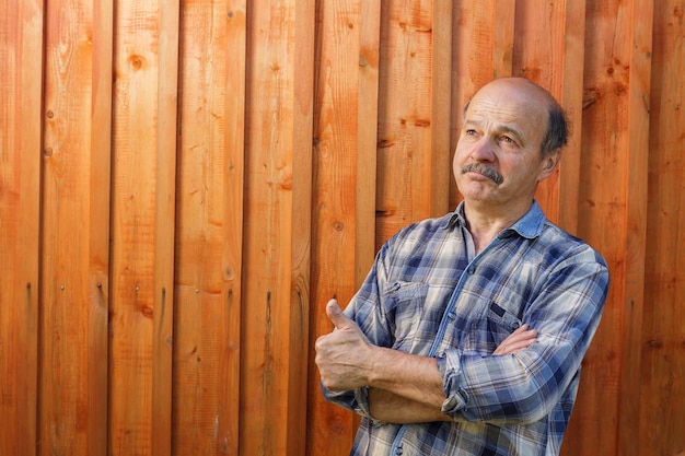 Homme âgé regardant rêveusement sur un fond de bois