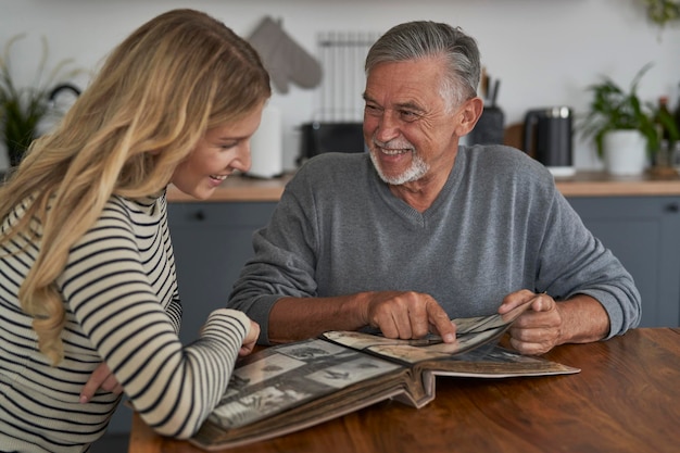 Un homme âgé rencontre sa fille adulte et regarde de vieilles photos dans un album.
