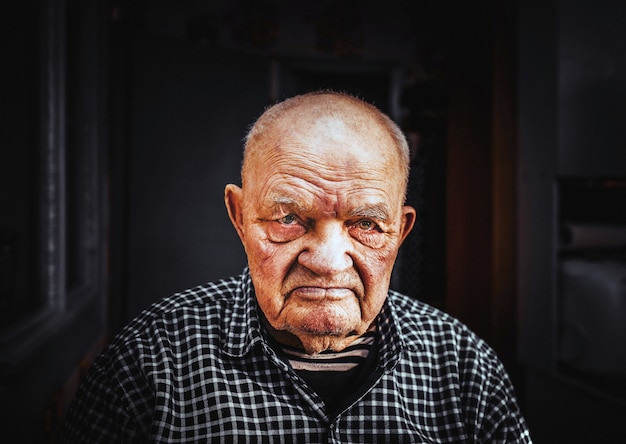 Un homme âgé - un retraité aux yeux beaux et gentils s'assoit et pense à l'arrière-plan de la vie