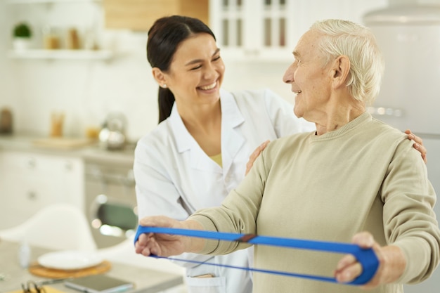 Homme âgé souriant et jeune infirmière se regardant