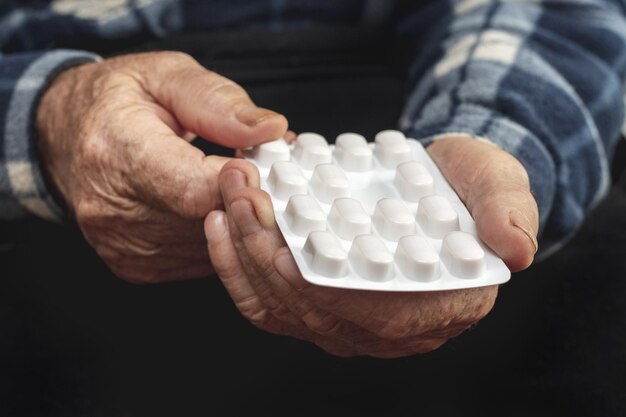 Un homme âgé tient des pilules dans une plaquette thermoformée dans ses mains Prendre des pilules pour traiter la maladie