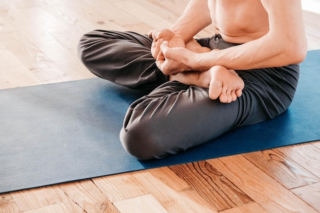 Homme âgé avec un torse nu assis dans une position méditative sur un tapis en studio