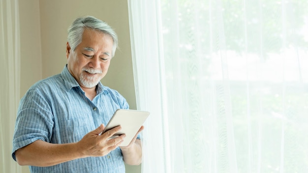 Homme âgé utilisant un smartphone souriant se sentir heureux dans la chambre à la maison concept senior de style de vie