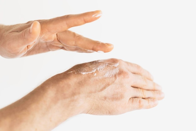 un homme âgé utilise une crème pour les mains en gros plan