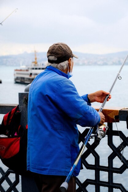 Photo un homme âgé en veste bleue tenant une canne à pêche