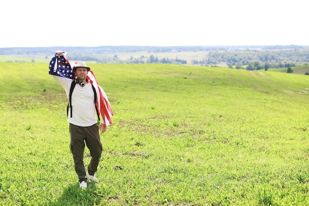 Homme agitant le drapeau américain debout dans le champ agricole de la ferme d'herbe, vacances, patriotisme, fierté, liberté, partis politiques, immigrant