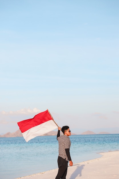 Un homme agitant le drapeau de l'Indonésie à la plage rose