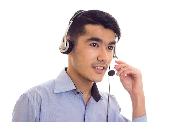 Homme agréable aux cheveux noirs en chemise bleue avec un casque noir sur fond blanc en studio