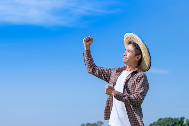 Homme agriculteur asiatique pose heureux et sourire avec un ciel bleu