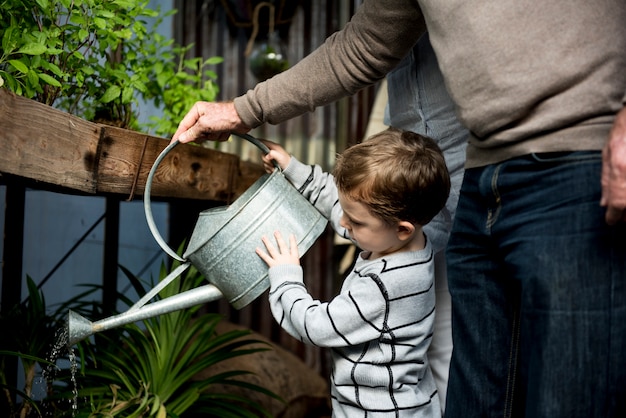 Photo homme aidant un jeune garçon à arroser les plantes