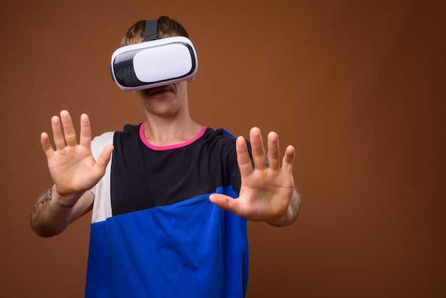 L'homme à l'aide d'un casque de réalité virtuelle contre un mur marron