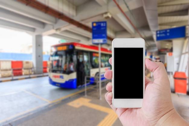 Homme à l&#39;aide de smartphone avec écran blanc sur l&#39;image floue de la gare routière