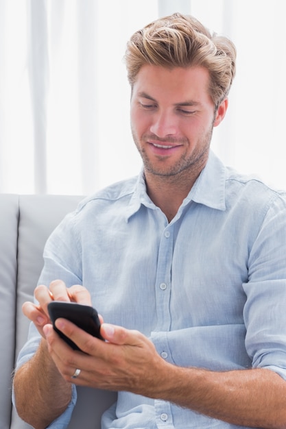 Homme à l&#39;aide de son smartphone sur un canapé