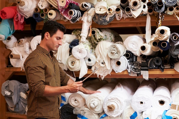 L'homme à l'aide de la tablette sélectionne le tissu des étagères de stockage