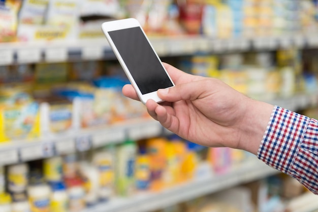 L'homme à l'aide de téléphone mobile libre tout en faisant du shopping dans un magasin