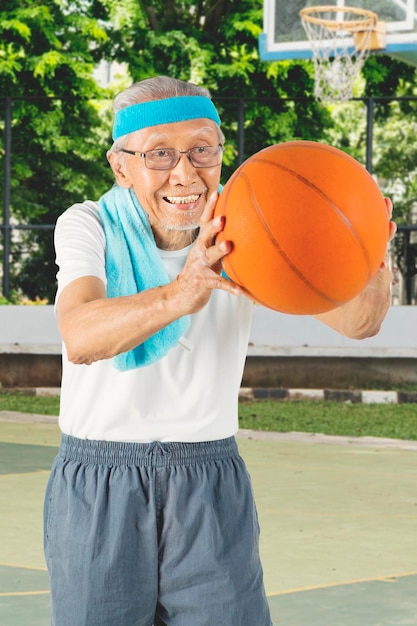 Photo homme aîné jouant au terrain de basket
