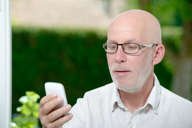 Homme aîné, lecture message, sur, smartphone