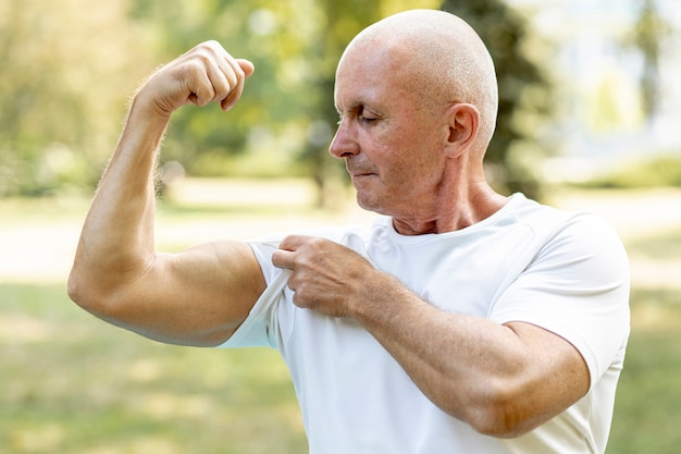 Homme aîné mâchant ses muscles