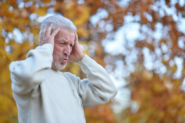 Homme aîné avec le mal de tête tenant des mains