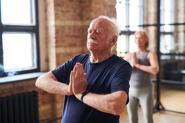 Homme aîné méditant pendant la classe de yoga