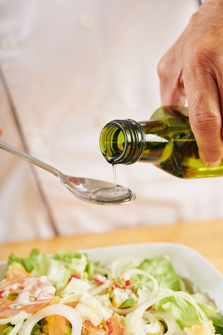 Homme ajoutant de l'huile dans la salade