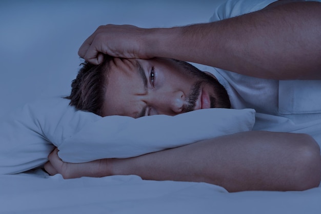 L'homme allongé dans le lit et essayant de dormir ne peut pas dormir Insomnie problèmes de sommeil ou troubles du sommeil