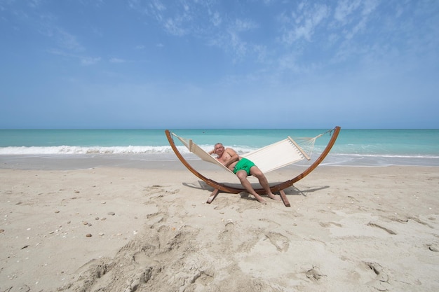 homme allongé sur un hamac reposant sur la plage