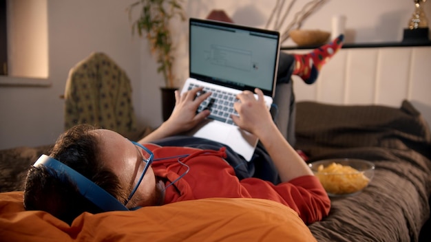 Homme allongé sur le lit et cherchant sur Internet