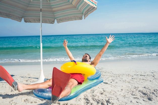 Homme allongé sur la plage avec des palmes et un anneau en caoutchouc