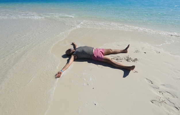 homme allongé sur le sable de la mer